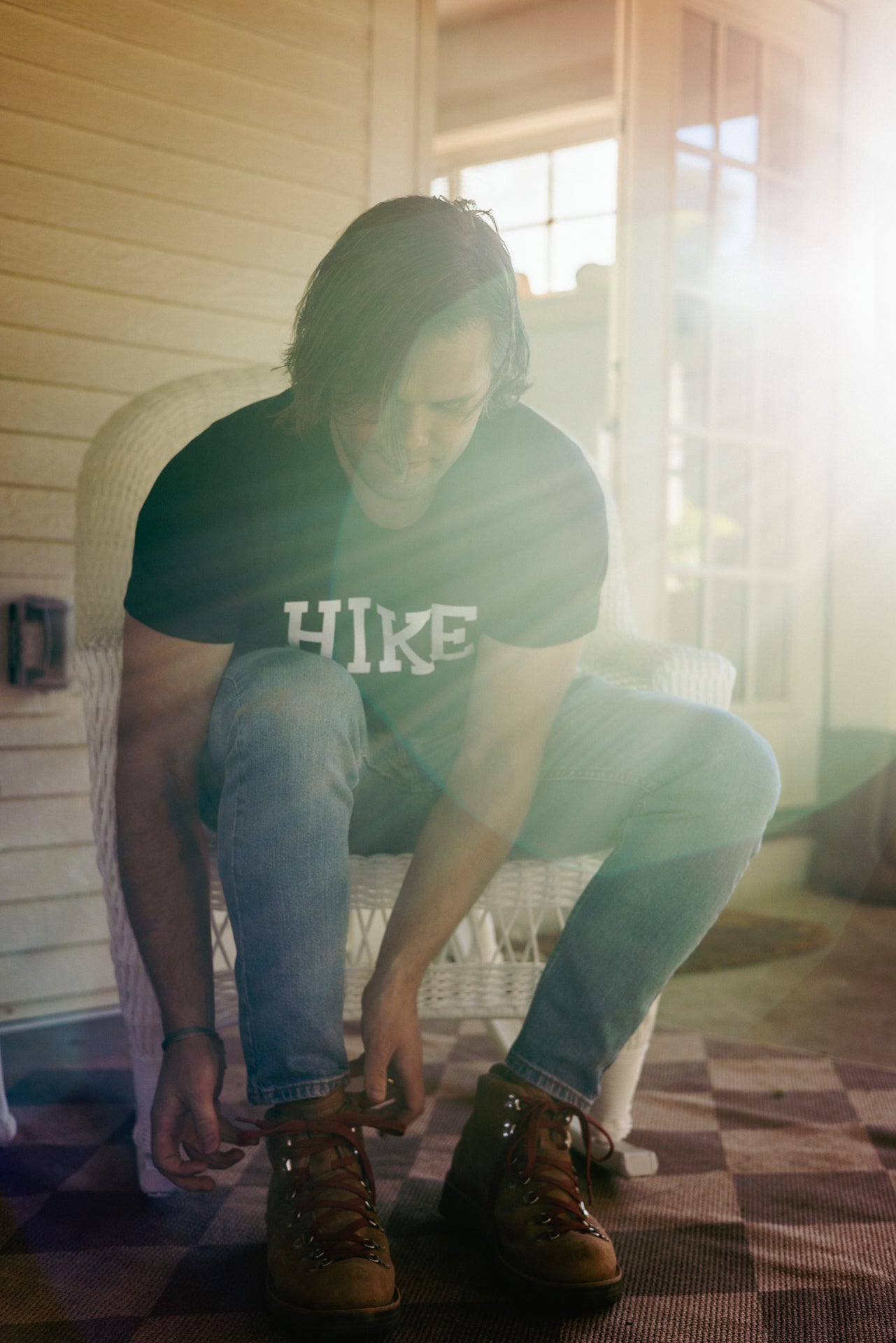 A hiker in the "The Hike T" shirt, tying his hiking boots getting ready to hike on a Utah trail with family and friends.