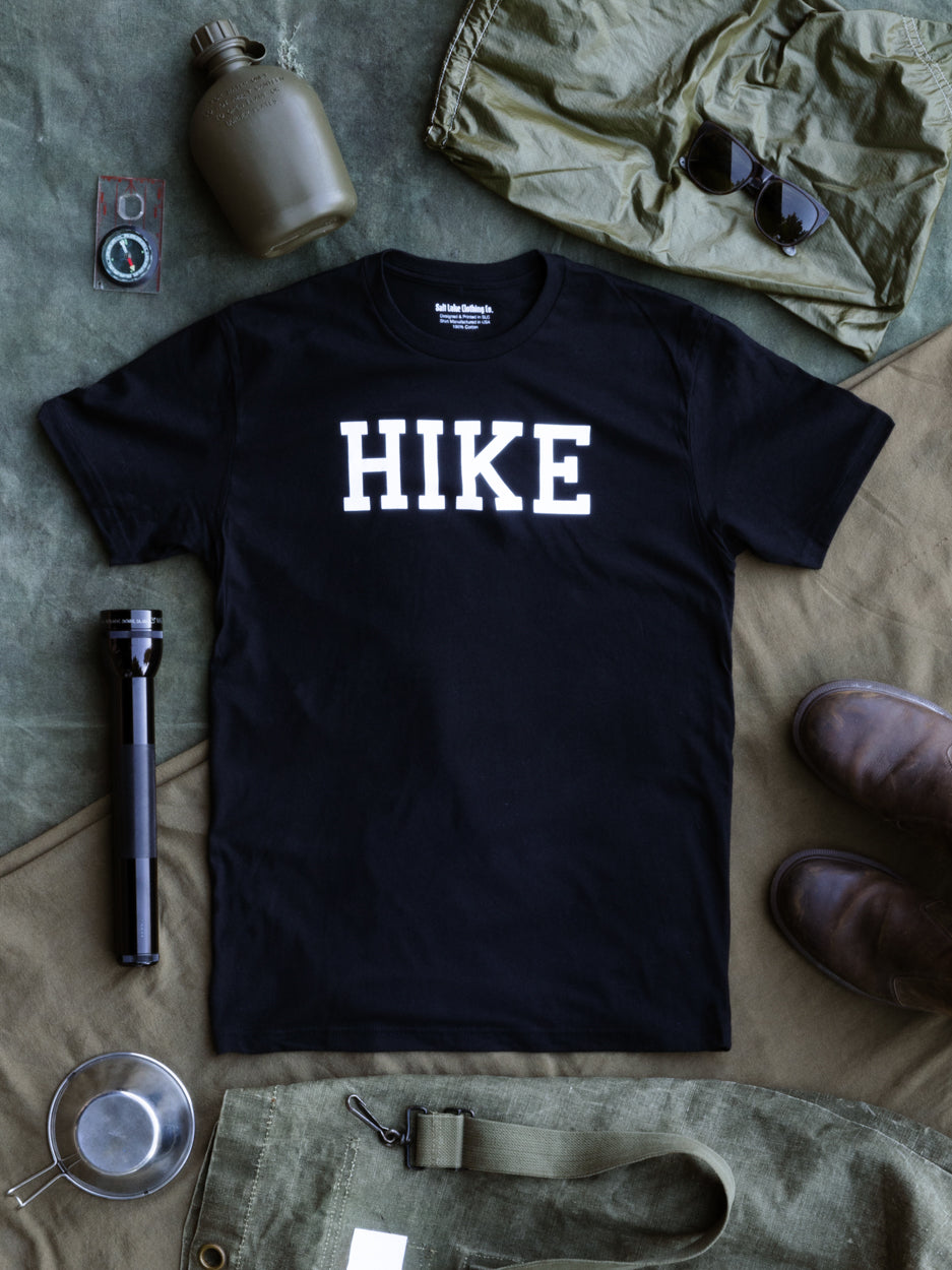 Flat lay photo of the Hike T - with camping accessories and trail gear laid to the side.