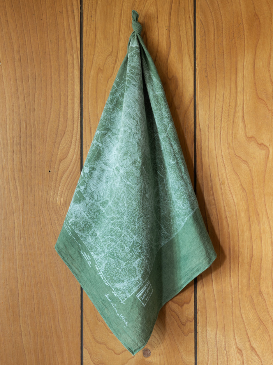 Wasatch Topographic Bandana hanging from a vintage wooden wall.